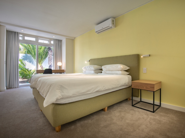 Camps Bay Villa Bedroom with double bed, air conditioner and view of small palm trees in courtyard
