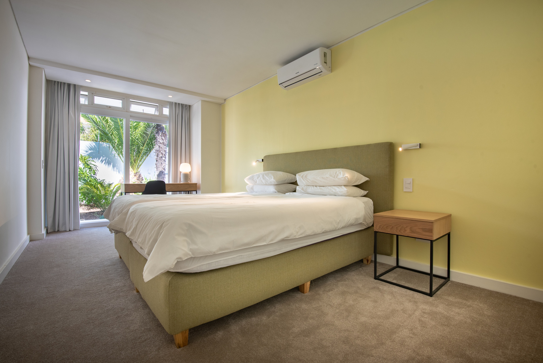 Camps Bay Villa Bedroom with double bed, air conditioner and view of small palm trees in courtyard